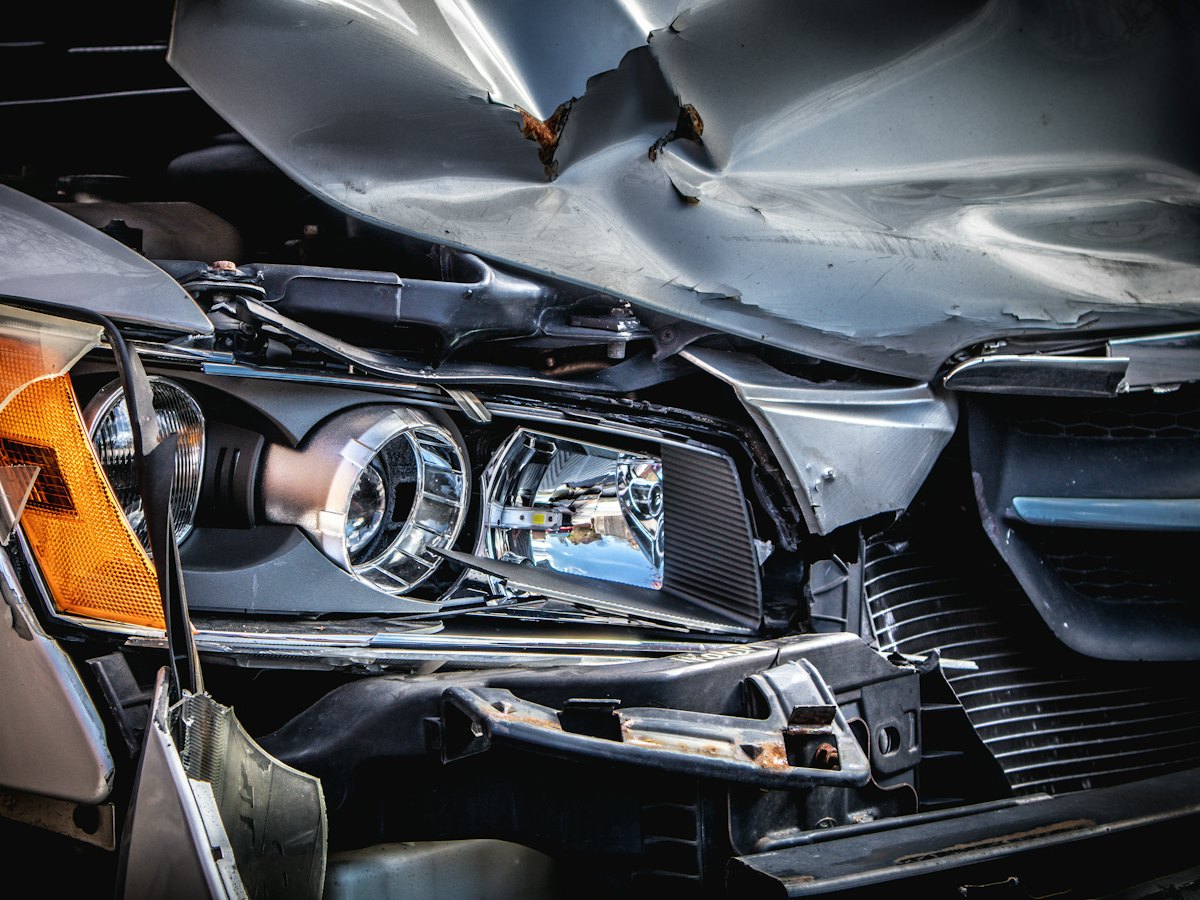 Front-end collision damage on a silver car awaiting repair