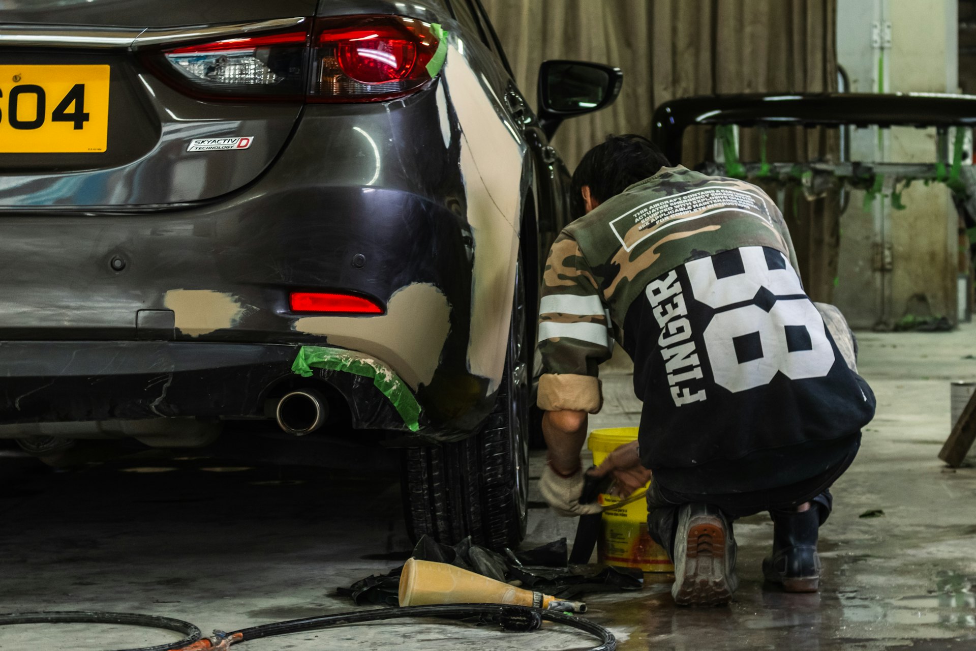 Technician refinishing a rear quarter panel inside the Chase Automotive body shop